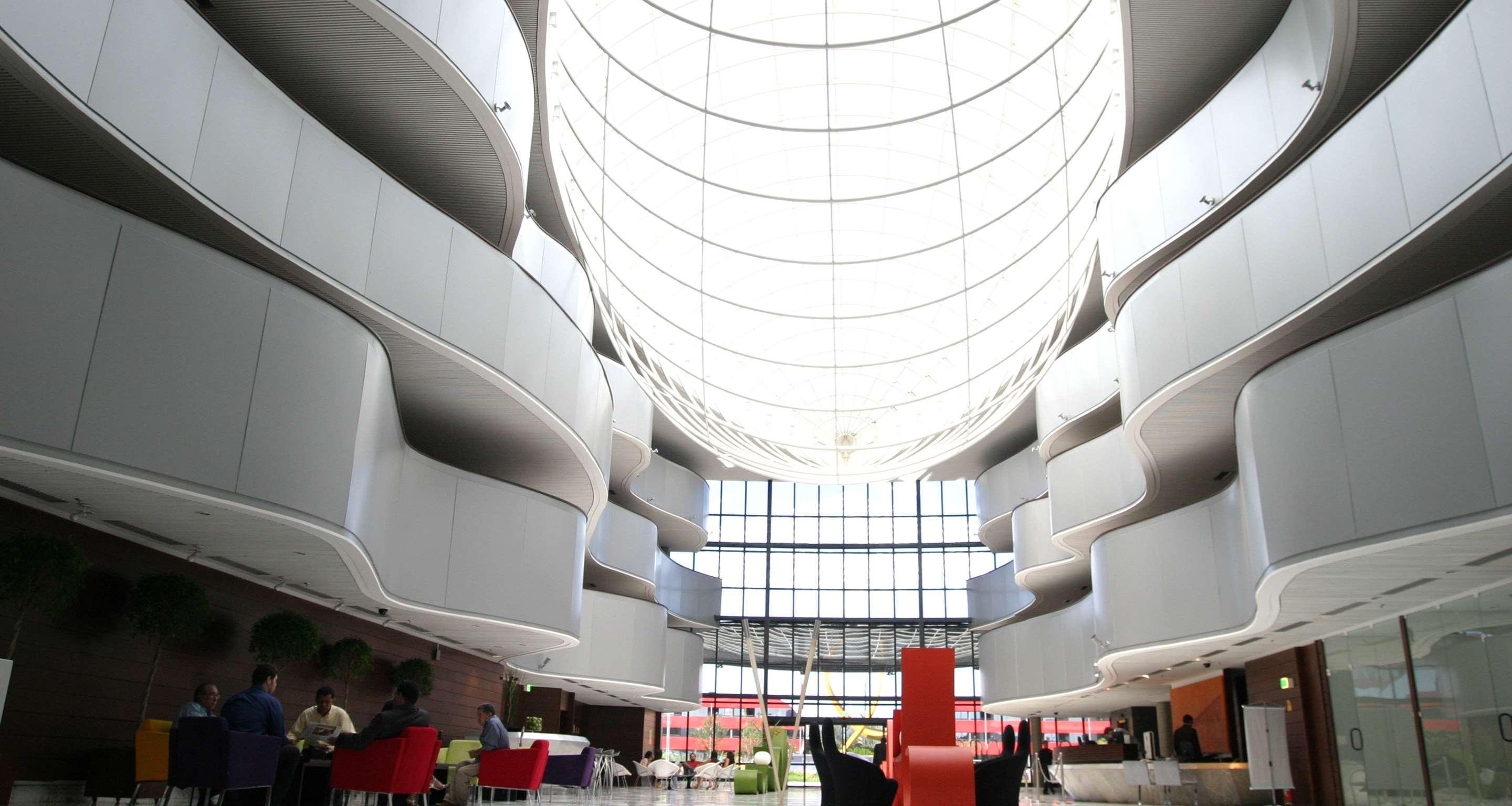 Royal Tulip Brasilia Alvorada Hotel Екстериор снимка The photo depicts a modern interior space characterized by sleek, curvilinear architecture. The ceiling features a large, dome-like skylight that allows natural light to flood the area. The walls display a minimalist design with smooth, white surface